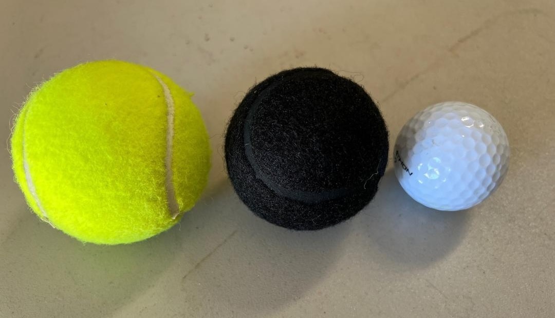 Size comparison between tennis ball, black cut ball, and golf ball